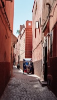 a small blue and red truck parked in a narrow alley