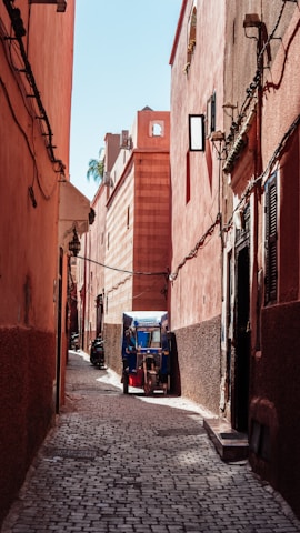 a small blue and red truck parked in a narrow alley