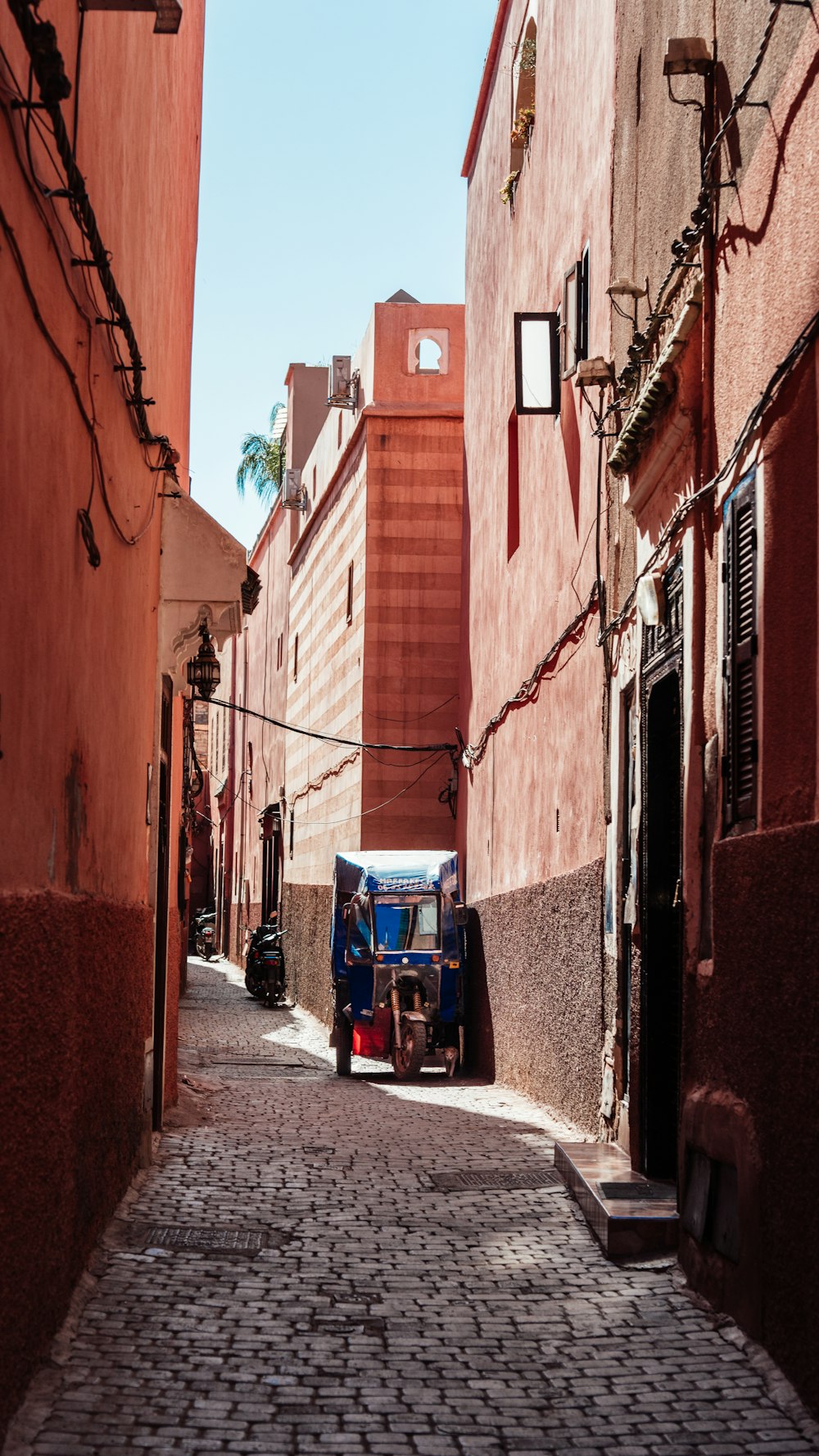 a small blue and red truck parked in a narrow alley