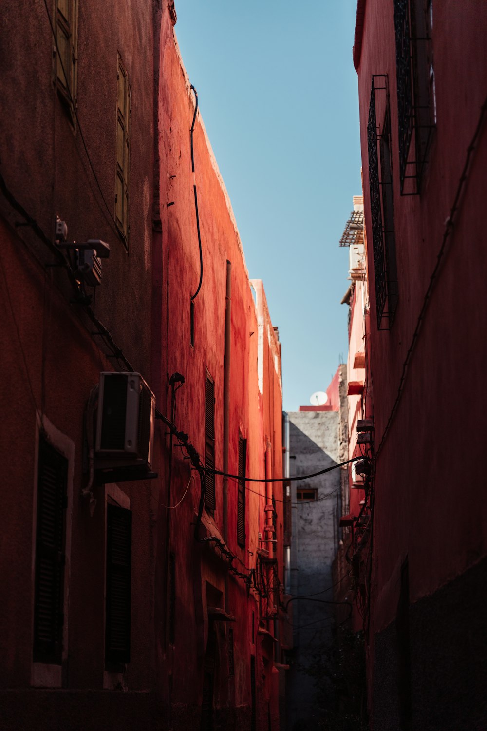 a narrow alley way with red buildings and a blue sky