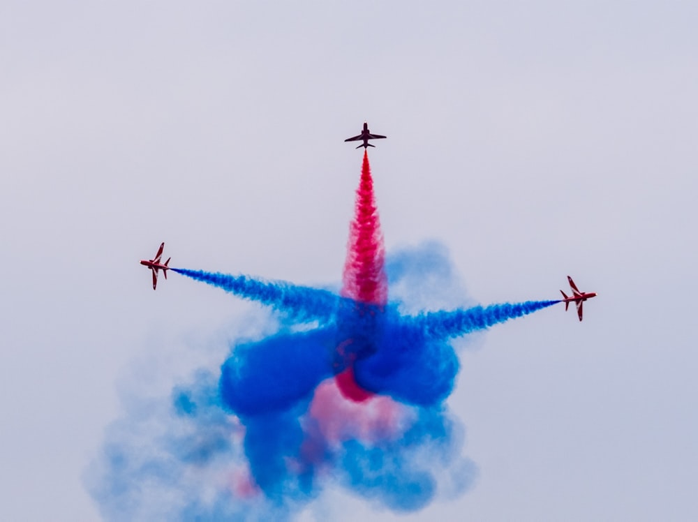 a group of red and blue jets flying through the sky