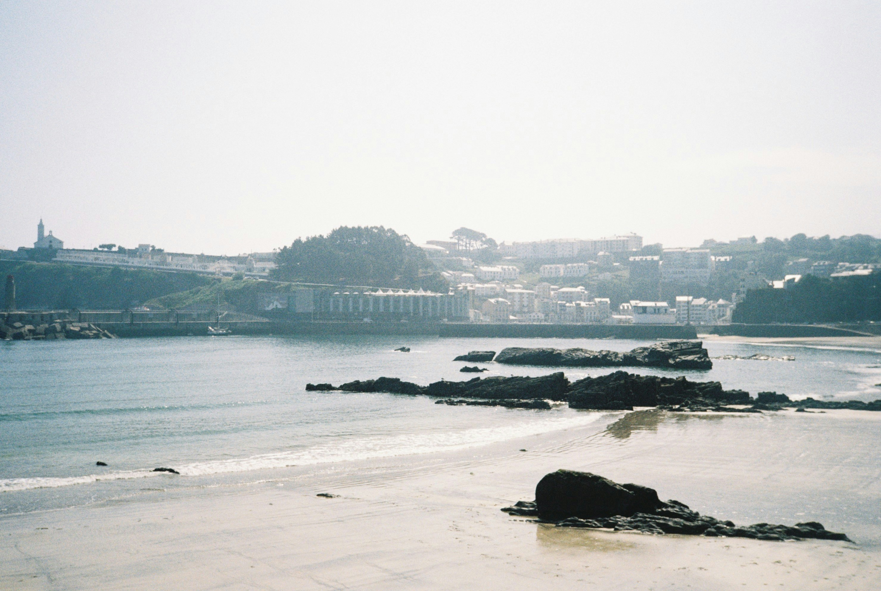 a beach with a body of water and a city in the background