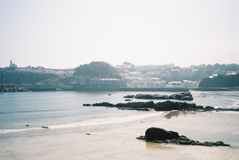 a beach with a body of water and a city in the background