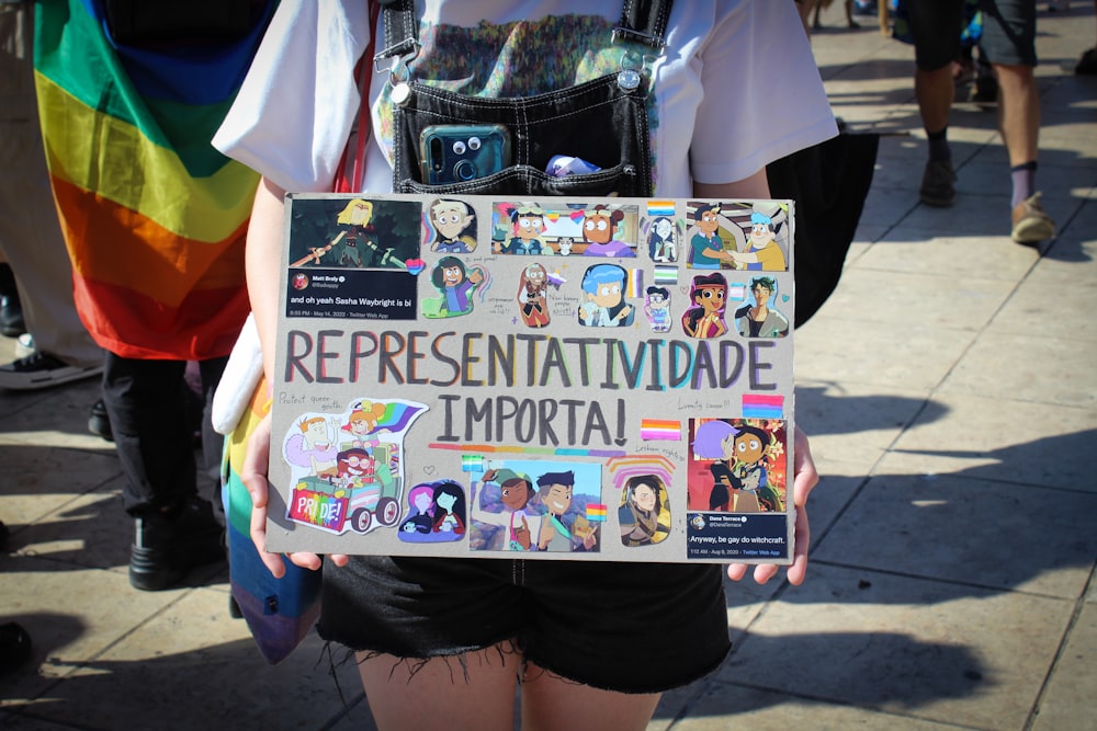 a person holding a sign with a bunch of stickers on it