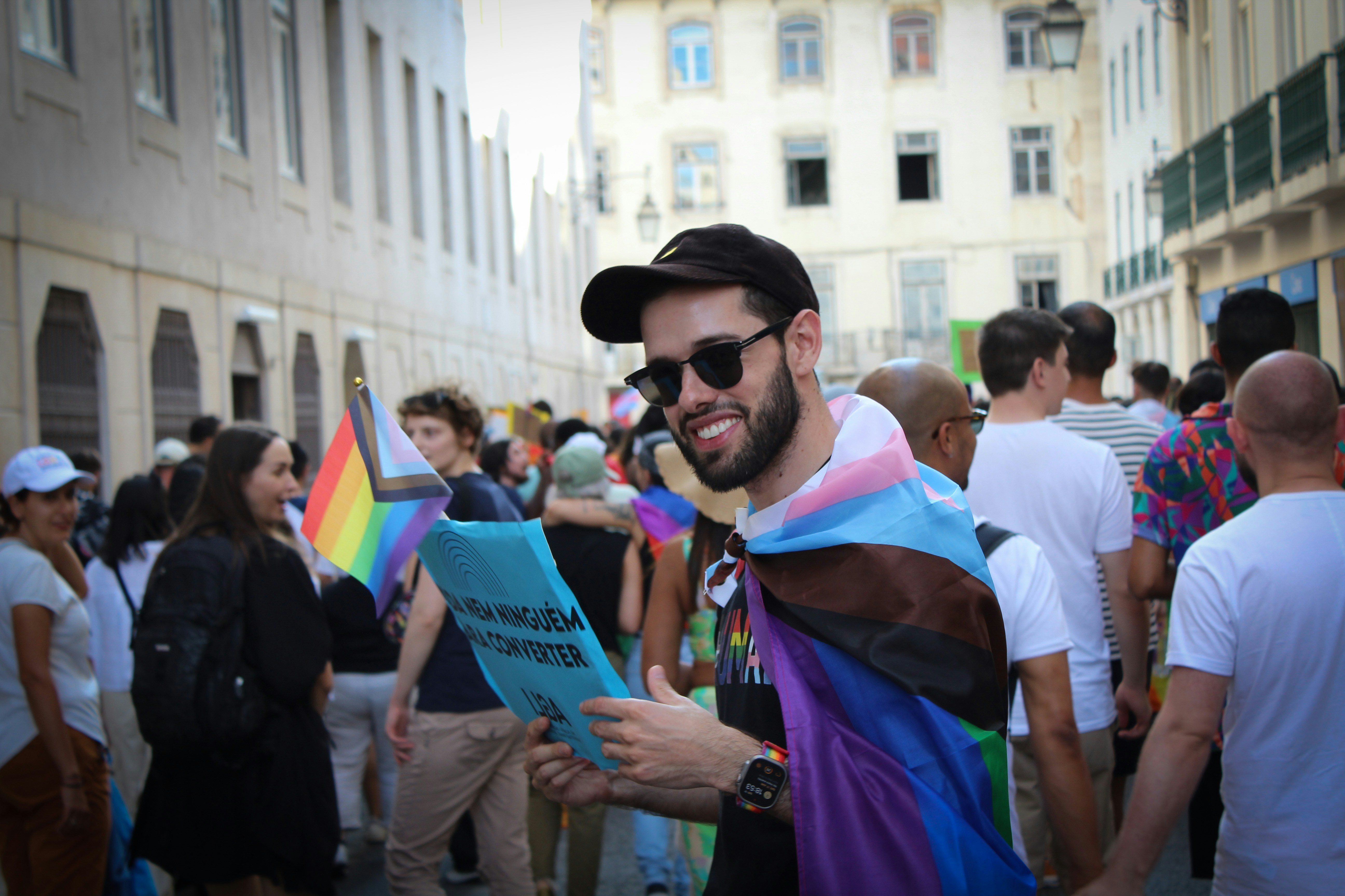 Un hombre con una capa de arco iris y sosteniendo un libro