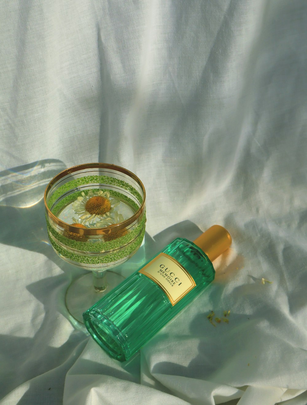 ein Parfümflakon neben einer Glasschale