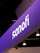 A prominently displayed sign with the name 'sanofi' is illuminated against a purple background. The sign seems to be part of an exhibition or conference setup, with multiple spotlights hanging from the ceiling.