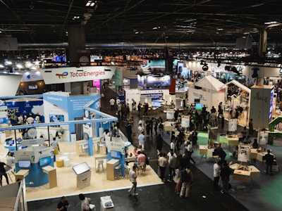 An exhibition space bustling with visitors and detailed booth setups.