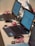 Several laptops with screens displaying a programming interface are arranged on a table. Pink USB cables and mice are connected to the laptops. Small electronic components are also present near the laptops.
