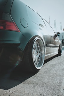 A sleek car with custom alloy wheels parked on a city street.