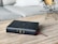 A black leather-bound Bible lies on a wooden table with a red ribbon bookmark. In the background, there's a modern star-shaped metal wire sculpture and a light gray sofa with a white pillow.