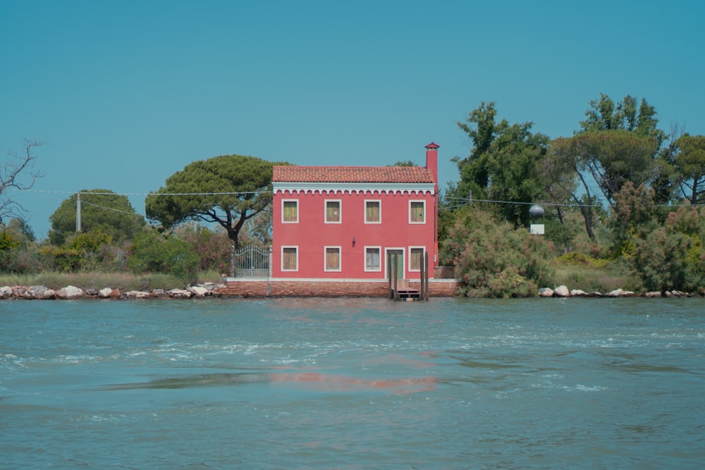 a red house sitting on top of a body of water