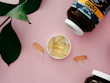 Fresh capsules spilling from a bottle onto a wooden surface with green leaves nearby