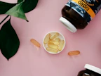 Fresh capsules spilling from a bottle onto a wooden surface with green leaves nearby
