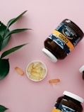 three bottles of vitamins sitting on top of a pink surface