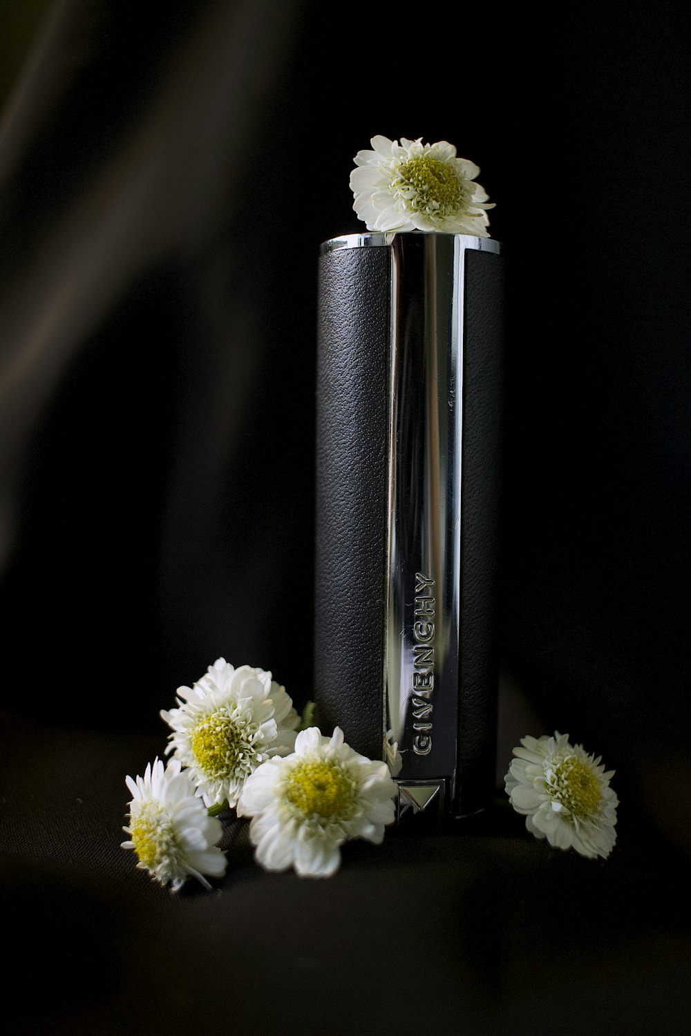 a couple of white flowers sitting next to a black tube