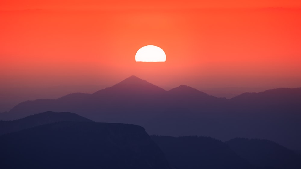 the sun is setting over a mountain range