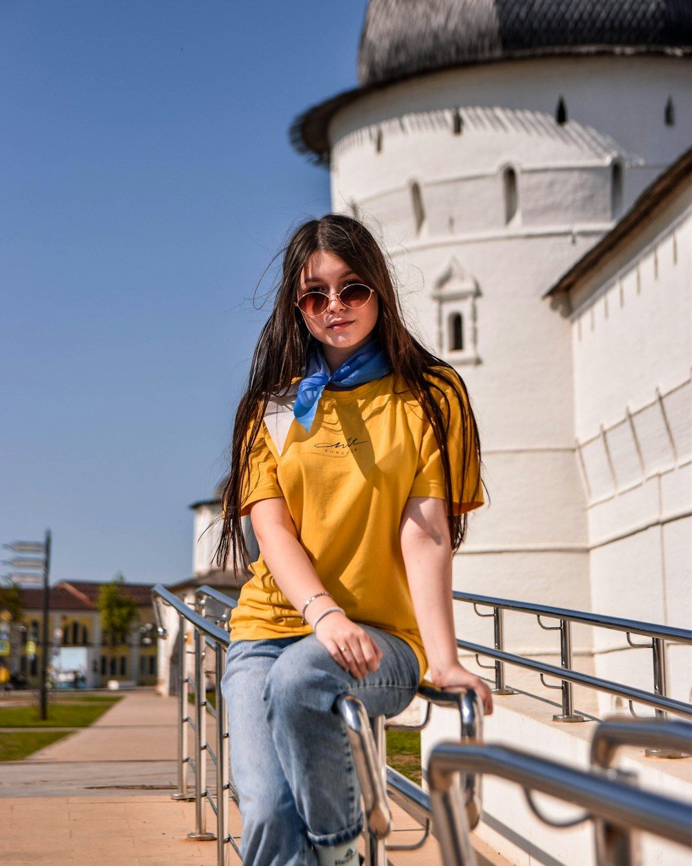 a young girl sitting on a railing next to a building