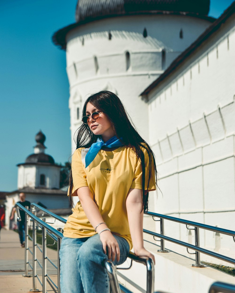 a woman sitting on a railing next to a white building