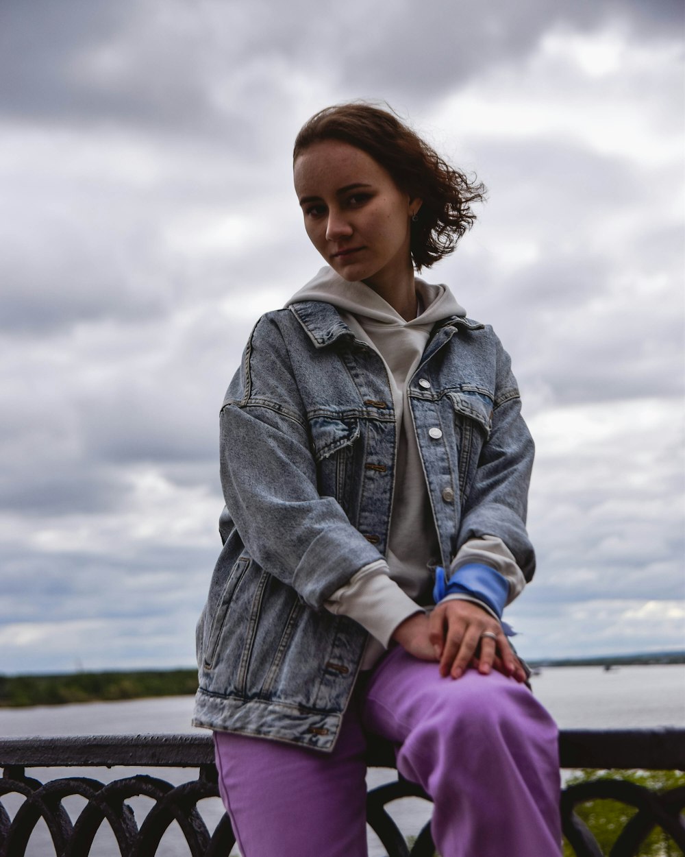 a woman sitting on a fence with her legs crossed