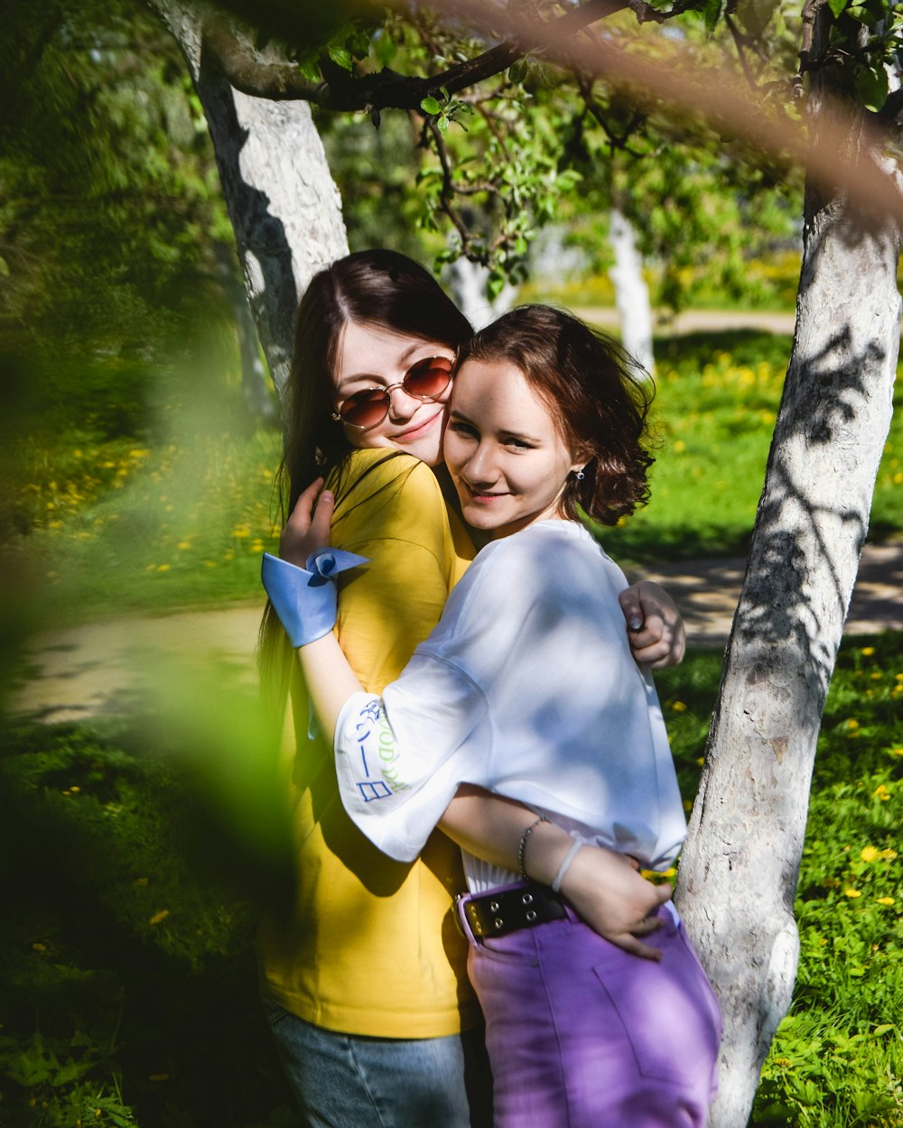 two girls hugging each other in a park