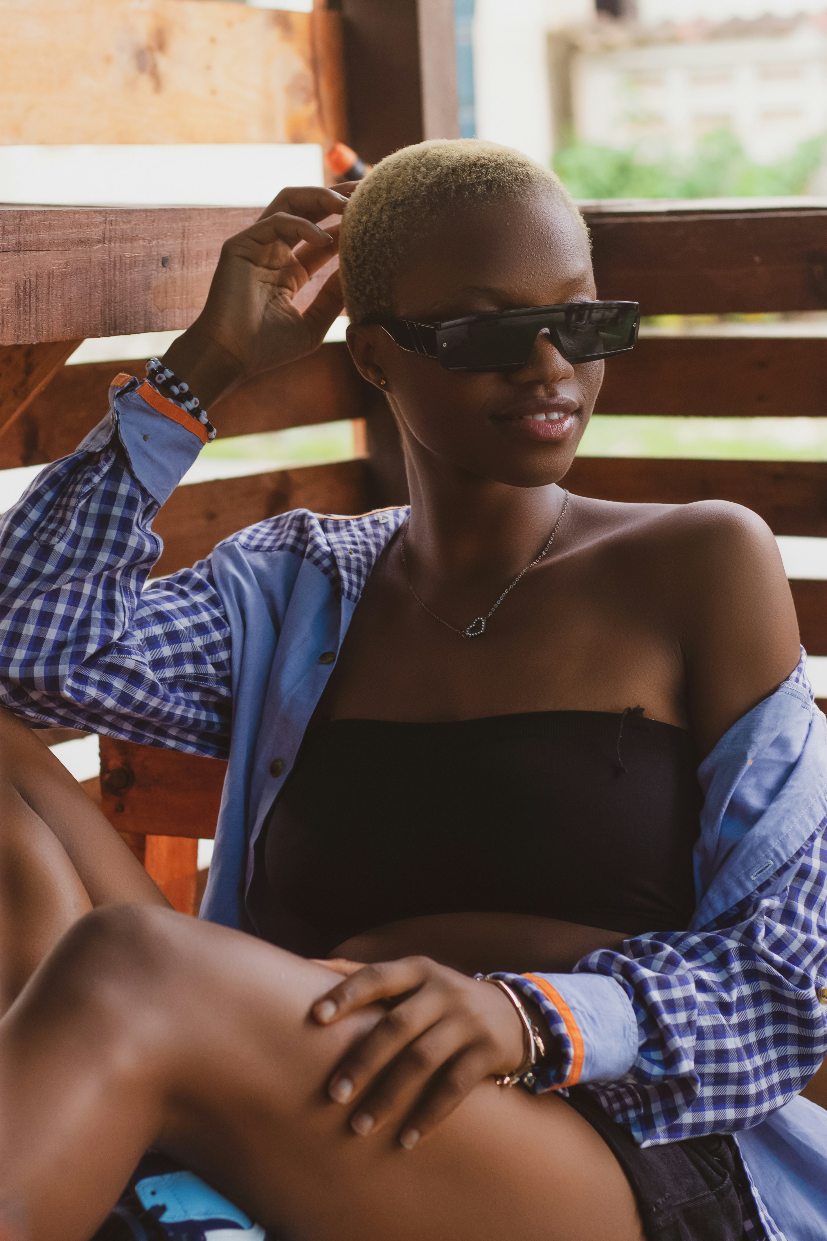 a woman sitting on a wooden bench wearing sunglasses