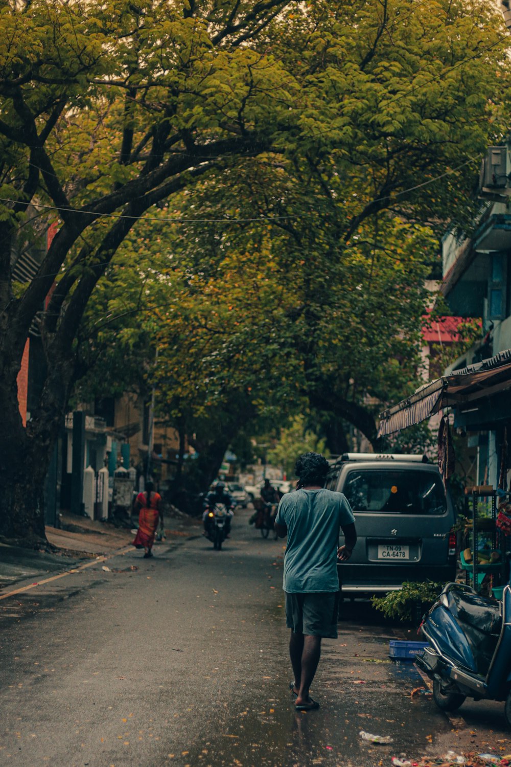 a man walking down a street next to a parked car