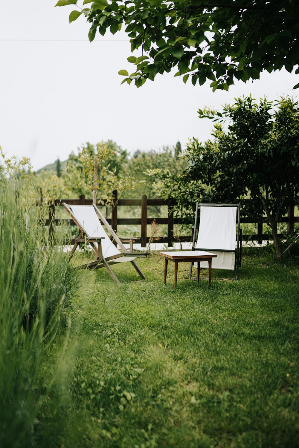 two lawn chairs sitting on top of a lush green field