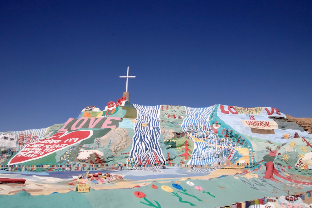 a cross on top of a hill covered in murals