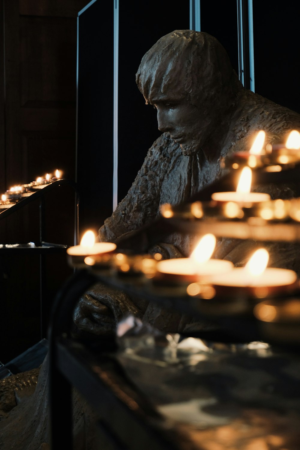 a statue of a person sitting in front of candles