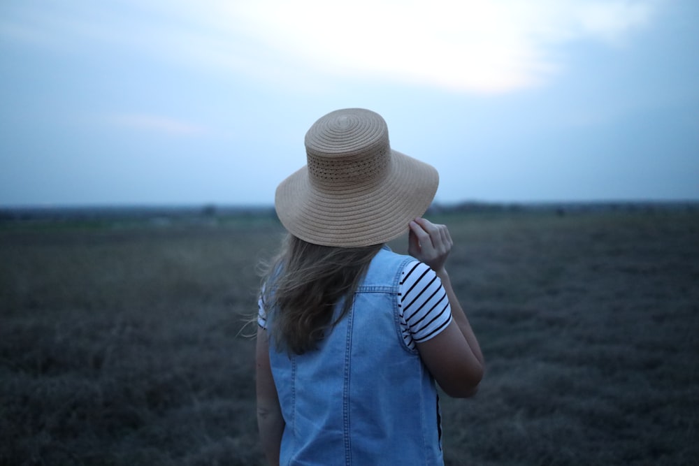 a woman wearing a hat standing in a field
