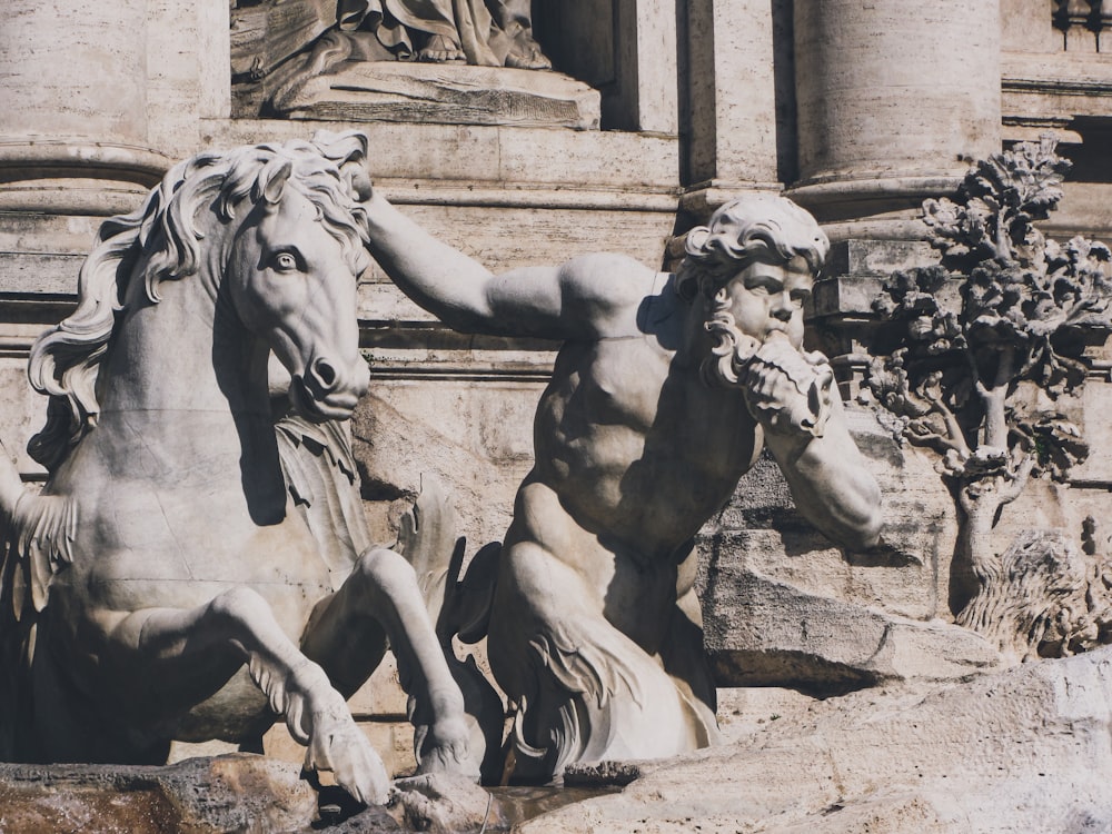 a statue of a man riding a horse next to a statue of a horse