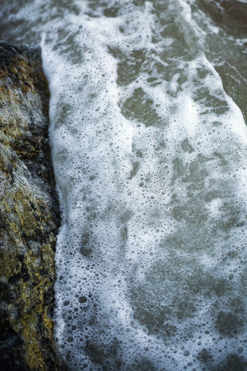 a surfboard sitting on top of a rock next to the ocean