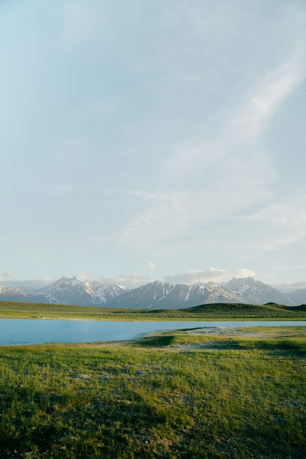 a large body of water surrounded by a lush green field