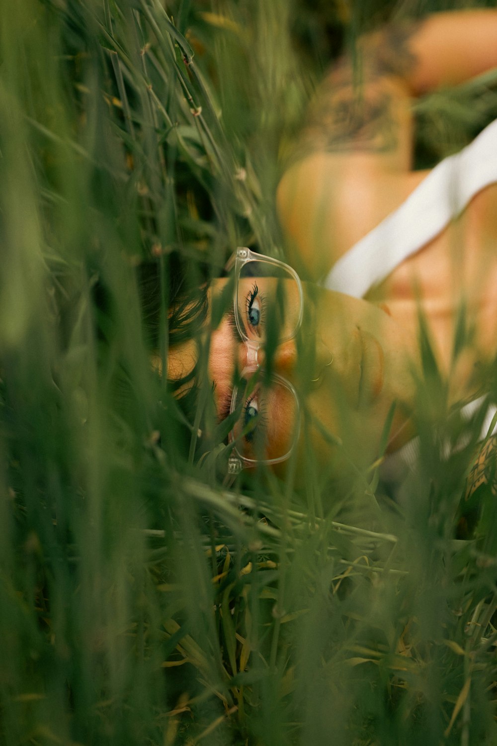 a woman laying in the grass holding a camera