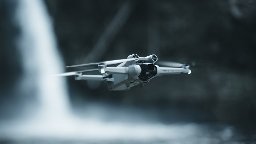 a close up of a remote control helicopter in front of a waterfall