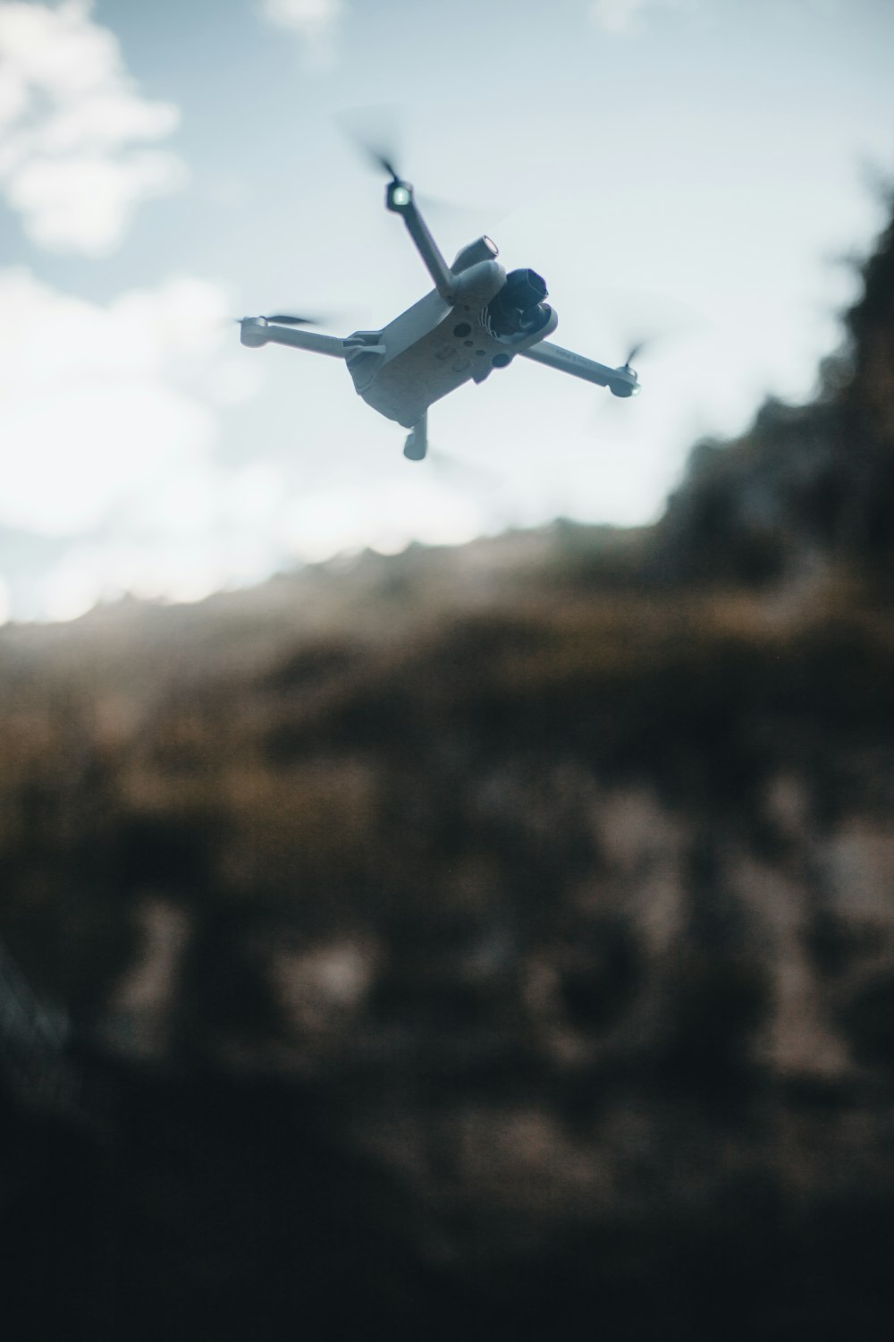 a small white helicopter flying over a mountain