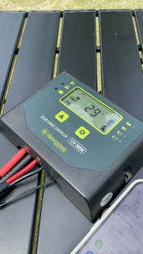 An electric current sensor attached to solar panel wiring with data display.