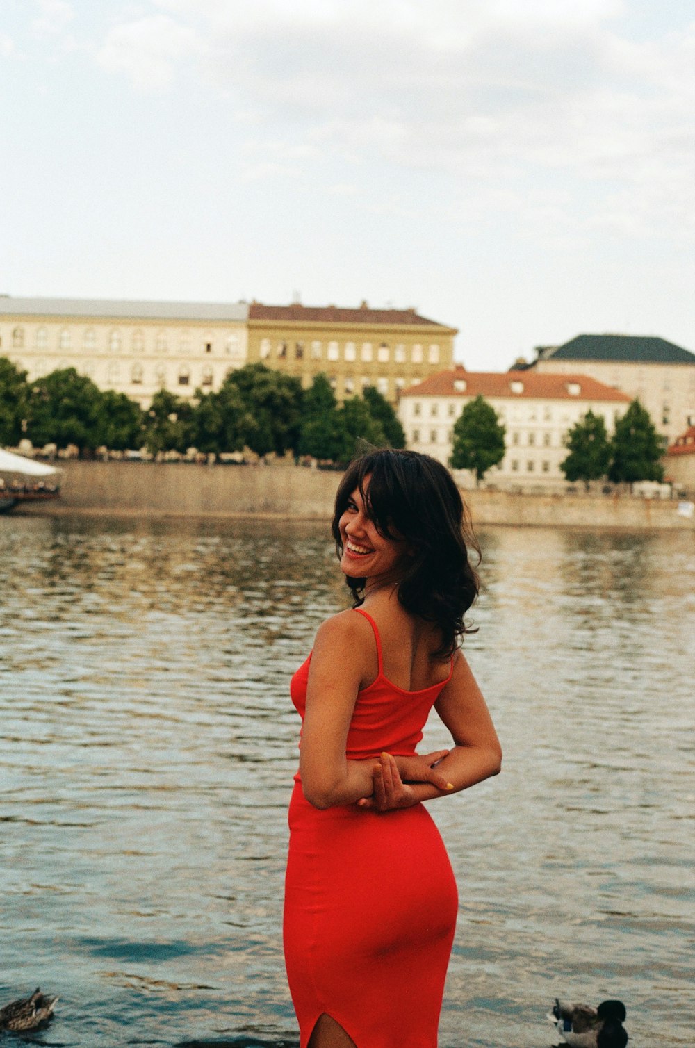 a woman in a red dress standing by a body of water