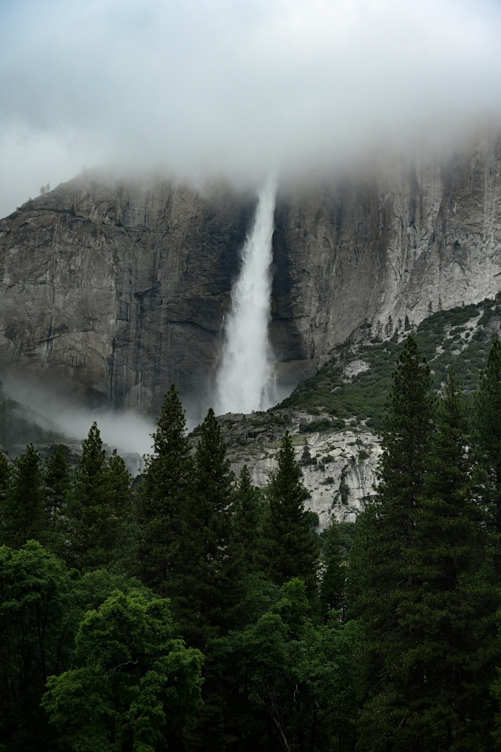 a very tall waterfall in the middle of a forest