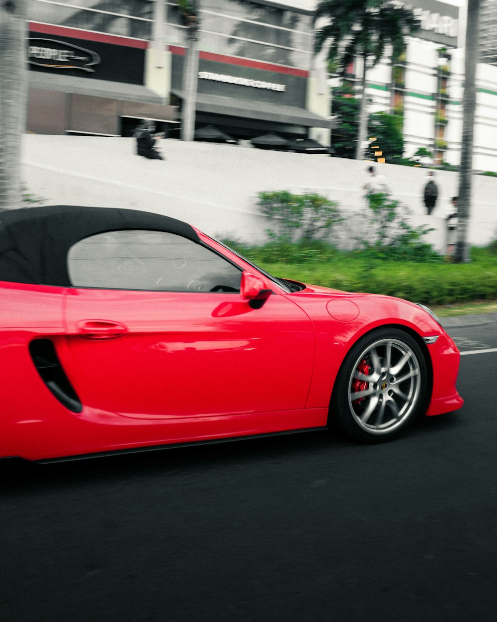 a red sports car driving down a street