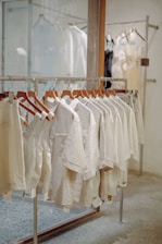 a rack of white shirts hanging in front of a mirror