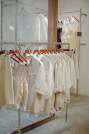 A stylish arrangement of women's wear showcasing flowing beige dresses and chic layered outfits against a soft gray backdrop.