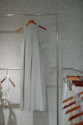A flowing dress hanging on a rustic hook against a textured wall, catching gentle sunlight.