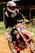 Close-up of a rider wearing sleek black and red Arko racewear, gripping motocross handlebars on a dirt track.