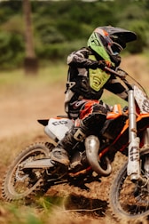 A close-up of dirtbike boots and gear kicking up dust as a rider takes a sharp turn.