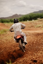 Close-up of a dirt bike rider navigating a rugged off-road trail.