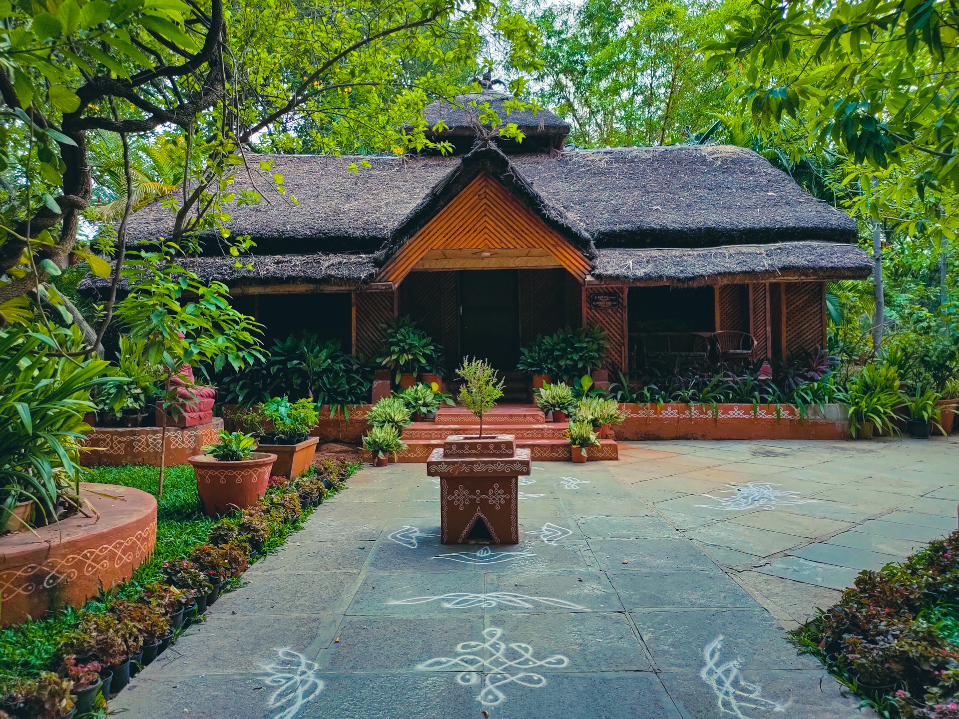 a house with a thatched roof surrounded by greenery