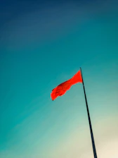 A red flag waving firmly against a stormy sky, representing suspension and boundary enforcement.
