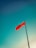 A single red flag is prominently displayed against a clear blue sky, attached to a tall pole.